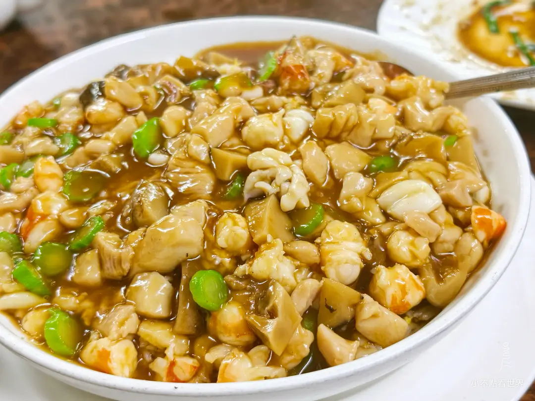 一大碗福州燴飯的特寫，燴飯上鋪滿了豐富的配料，包含蝦仁、切塊的香菇、肉丁與青菜丁，淋上濃稠的醬汁。